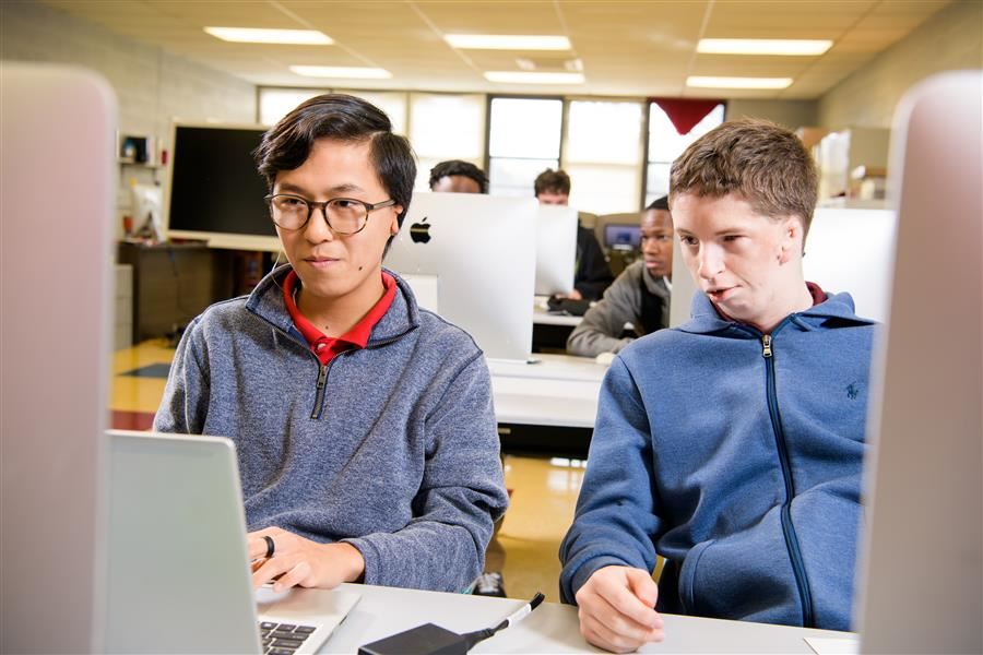   Two students work together on an assignment for Photoshop/Adobe Illustrator Class.